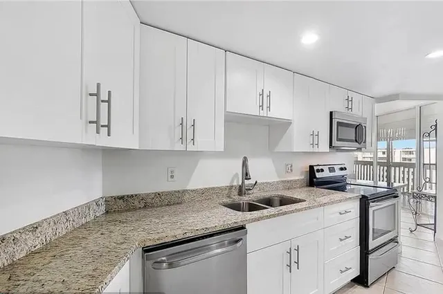 a kitchen with stainless steel appliances granite countertop a sink a stove and cabinets