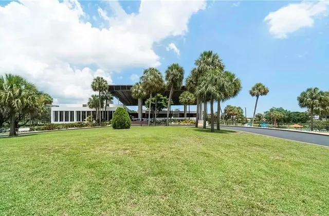 a view of a house with a big yard and palm trees