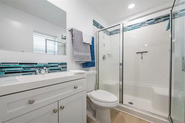 a bathroom with a shower sink vanity mirror and toilet
