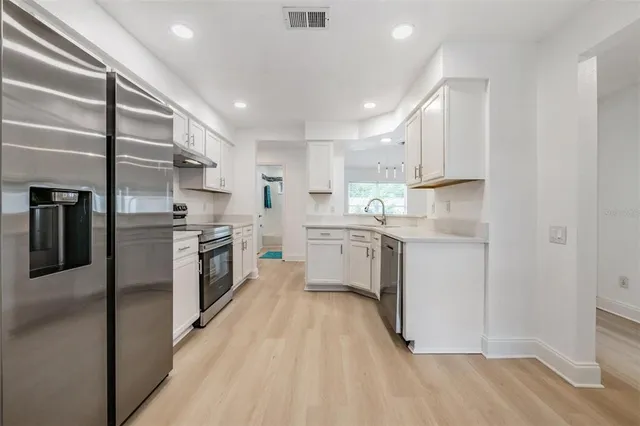 a kitchen with white cabinets and stainless steel appliances