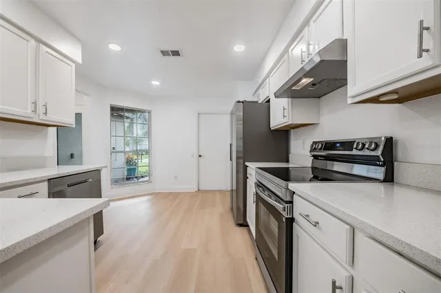 a kitchen with stainless steel appliances kitchen island granite countertop a stove a sink and a refrigerator