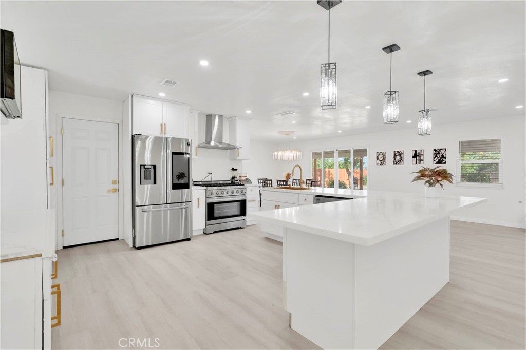 8263 3rd Avenue Hesperia, CA 92345 - Photo 13 of 56 a kitchen with stainless steel appliances kitchen island granite countertop a refrigerator a sink dishwasher a oven and white cabinets with wooden floor