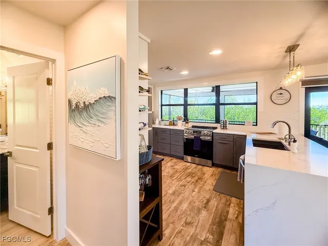 a large white kitchen with kitchen island a large window a sink and stainless steel appliances