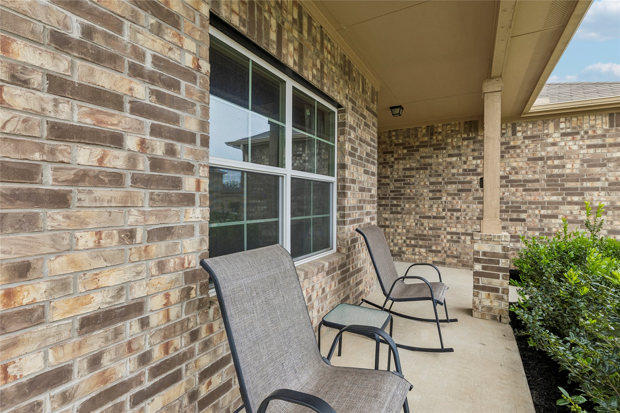 14409 Estuary Road Manor, TX 78653 - Photo 2 of 24 Covered front porch featuring a multi-toned brick facade, a single-pane window with grid inserts, and a textured concrete surface