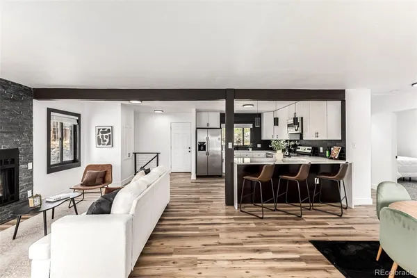 a living room with stainless steel appliances furniture a rug and a kitchen view