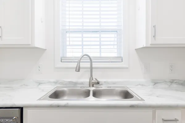 a kitchen sink with a window and white cabinets