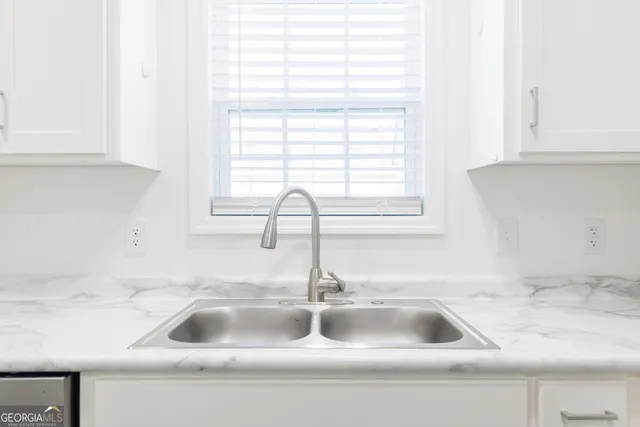 a kitchen sink with a window and white cabinets