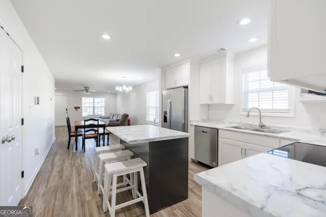 a kitchen with appliances a sink a counter top space and a center island