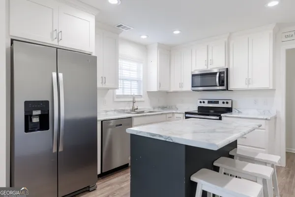 a kitchen with a refrigerator a sink cabinets and wooden floor
