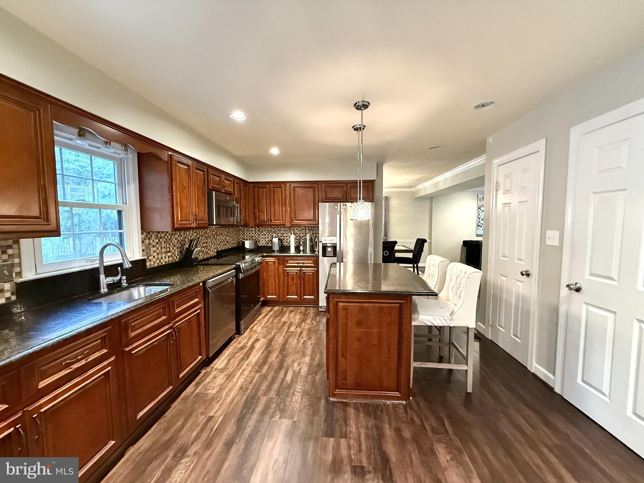 6421 Spring Lake Drive Burke, VA 22015 - Photo 12 of 65 a large kitchen with stainless steel appliances microwave refrigerator dining table and chairs