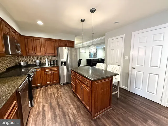 a kitchen with granite countertop a sink a counter space cabinets and stainless steel appliances