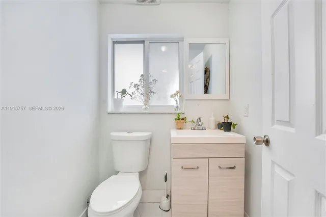 a bathroom with a toilet sink vanity and mirror
