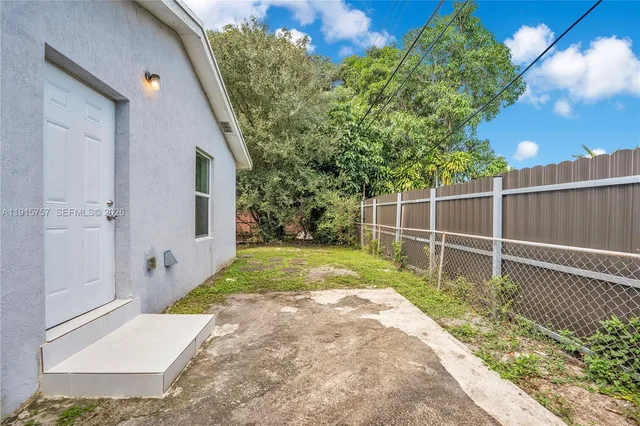 a backyard of a house with plants and large tree