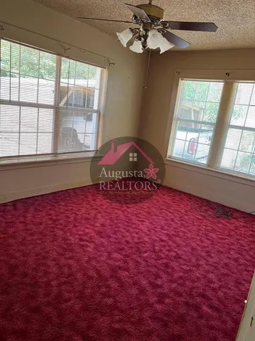 an empty room with windows and ceiling fan