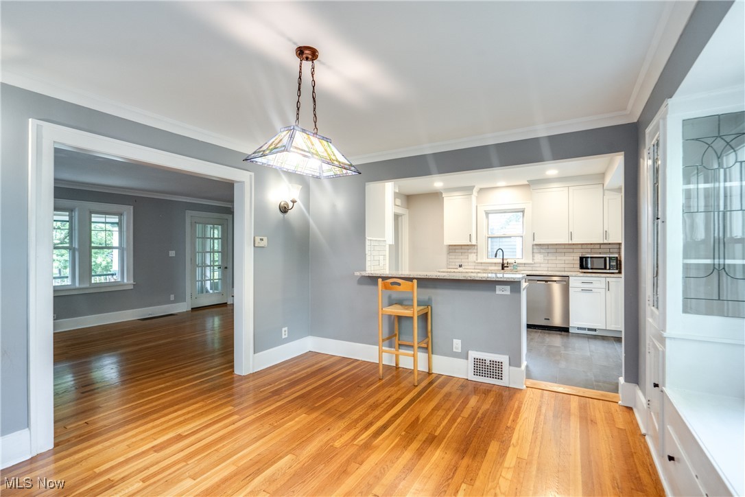 3130 Corydon Road Cleveland, OH 44118 - Photo 14 of 44 Kitchen featuring white cabinets, pendant lighting, appliances with stainless steel finishes, light hardwood / wood-style flooring, and a kitchen breakfast bar