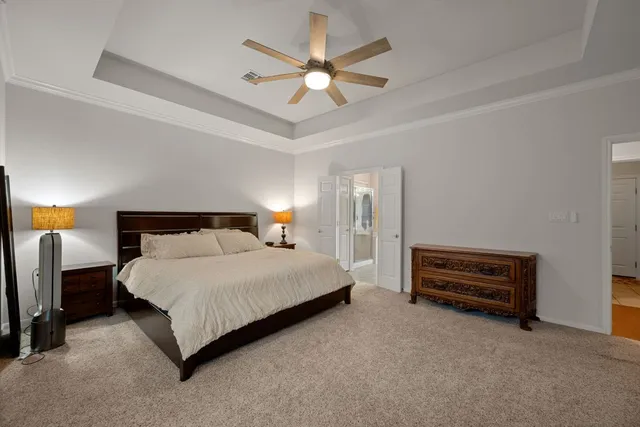 a bedroom with a bed a dresser and a chandelier