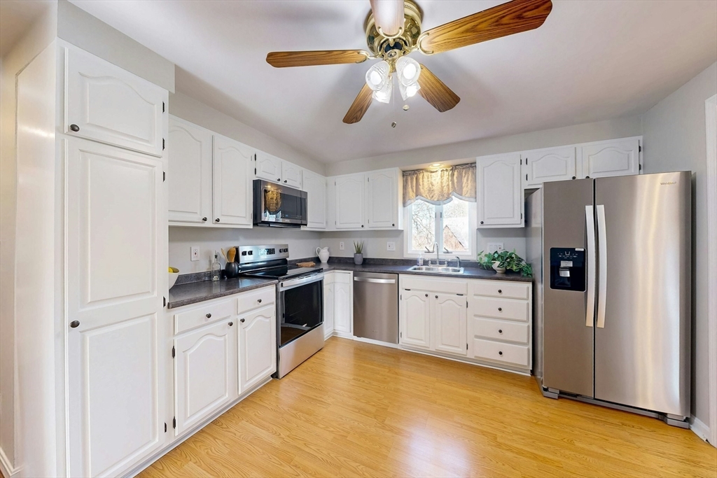 1 Hodge Road Arlington, MA 02474 - Photo 10 of 39 a kitchen with granite countertop a refrigerator a sink and dishwasher a stove top oven with white cabinets