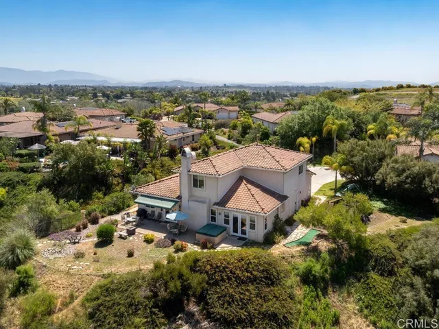 an aerial view of residential houses with outdoor space and trees