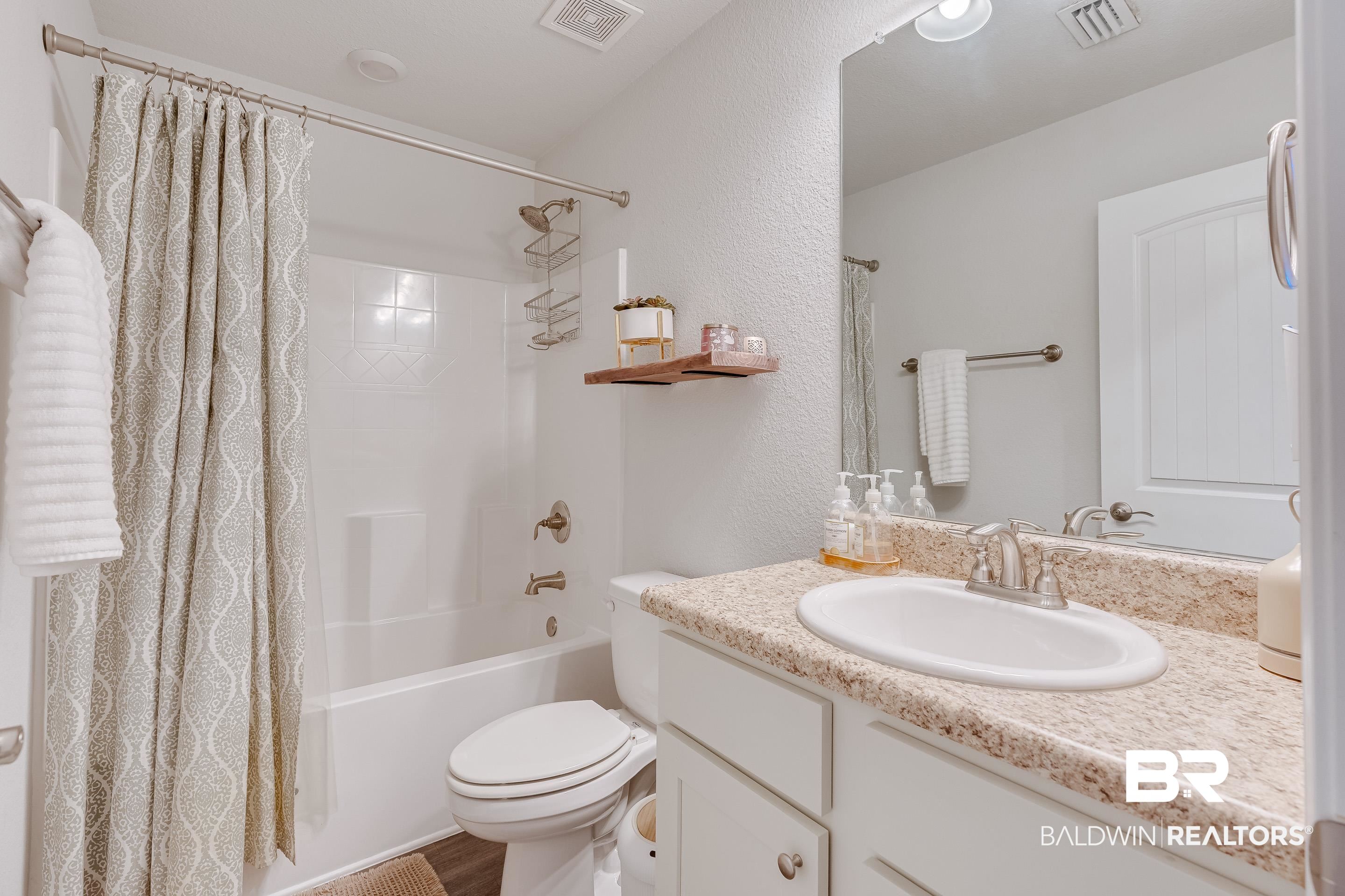 2215 Fernwood Loop West Semmes, AL 36575 - Photo 21 of 40 Bathroom featuring an integrated bathtub and shower, a single vanity with an oval sink, a speckled countertop, and wood-finish flooring