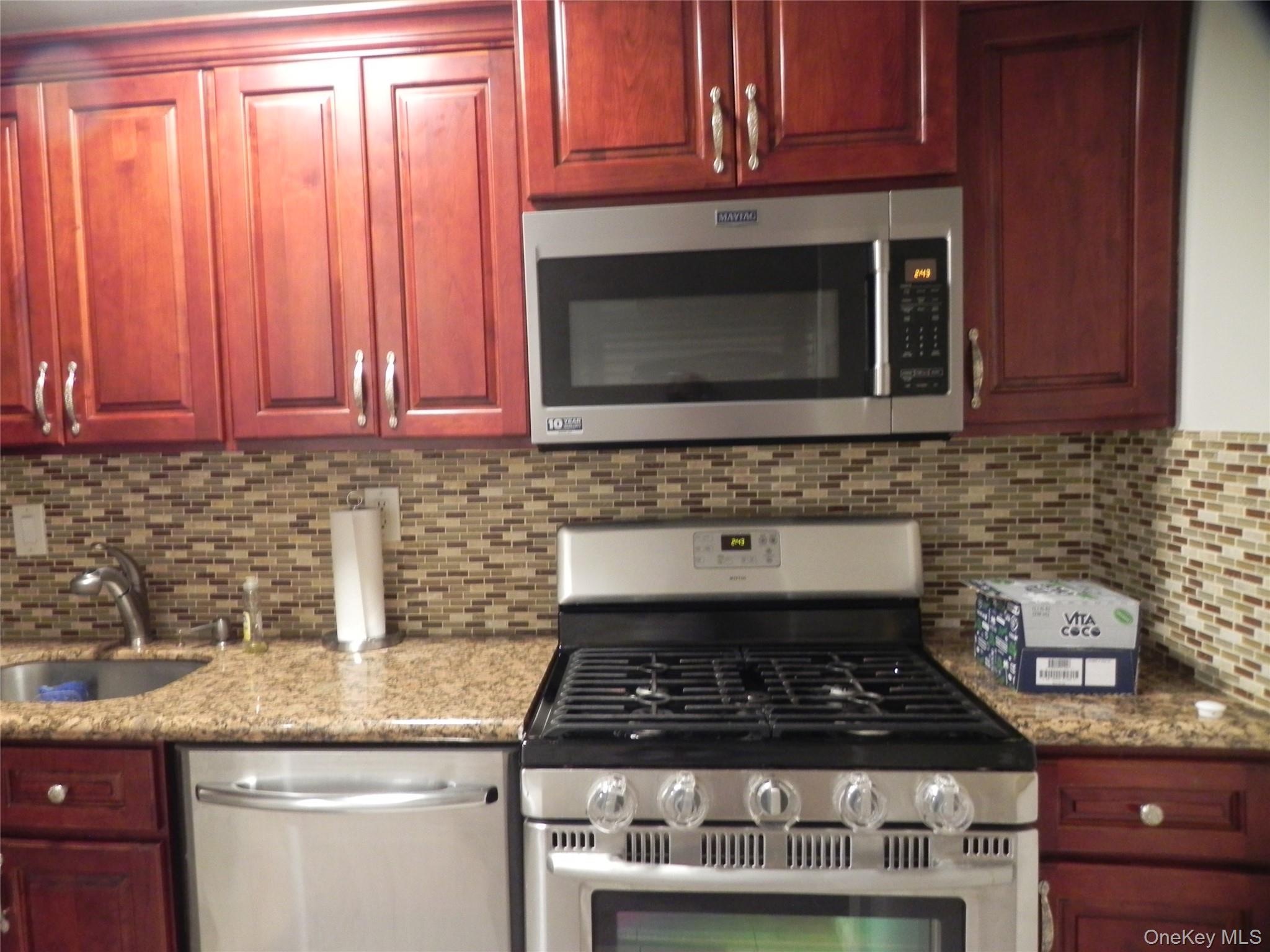 1250 North Avenue, Unit 110 New Rochelle, NY 10804 - Photo 10 of 27 Kitchen featuring stainless steel appliances, reddish brown cabinets, backsplash, and light stone countertops