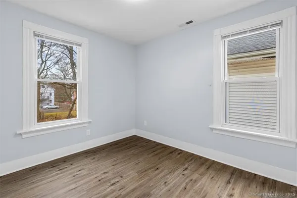 a view of an empty room with wooden floor and a window