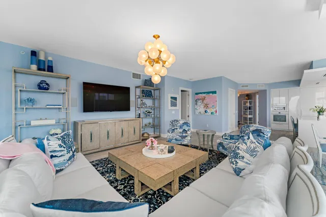 a living room with furniture a flat screen tv and a chandelier