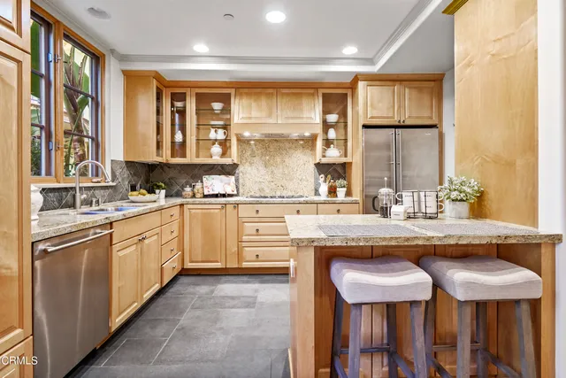 a kitchen with stainless steel appliances granite countertop a sink and chairs