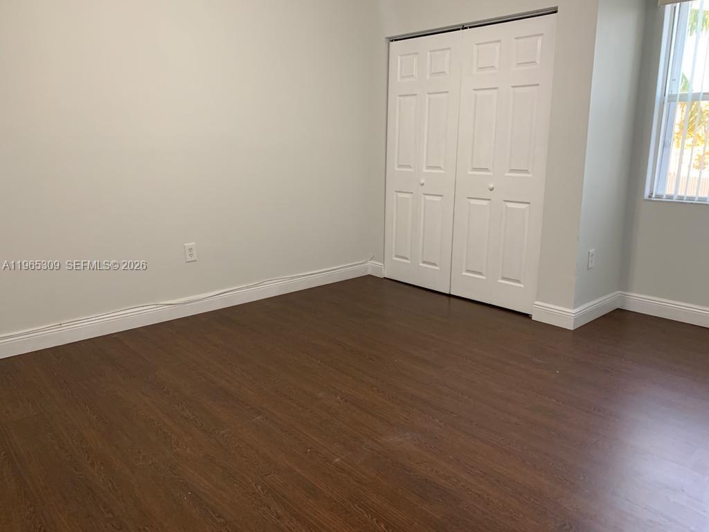 12447 Northwest 7th Street Miami, FL 33172 - Photo 22 of 29 an empty room with wooden floor and windows with curtains