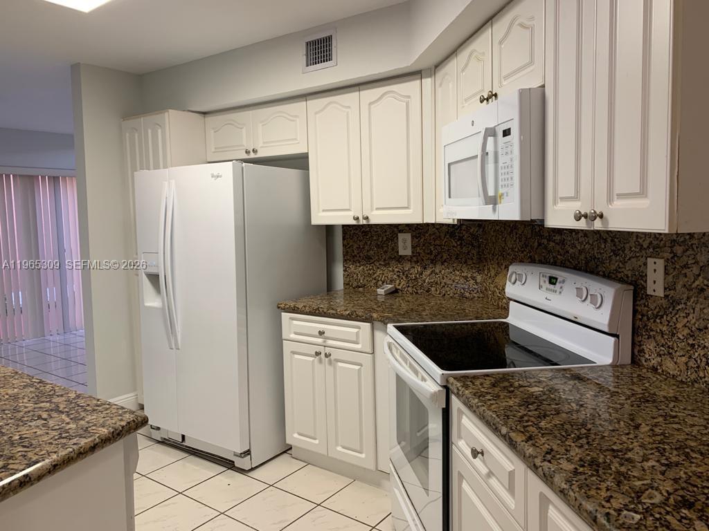 12447 Northwest 7th Street Miami, FL 33172 - Photo 7 of 29 a kitchen with granite countertop white cabinets and refrigerator