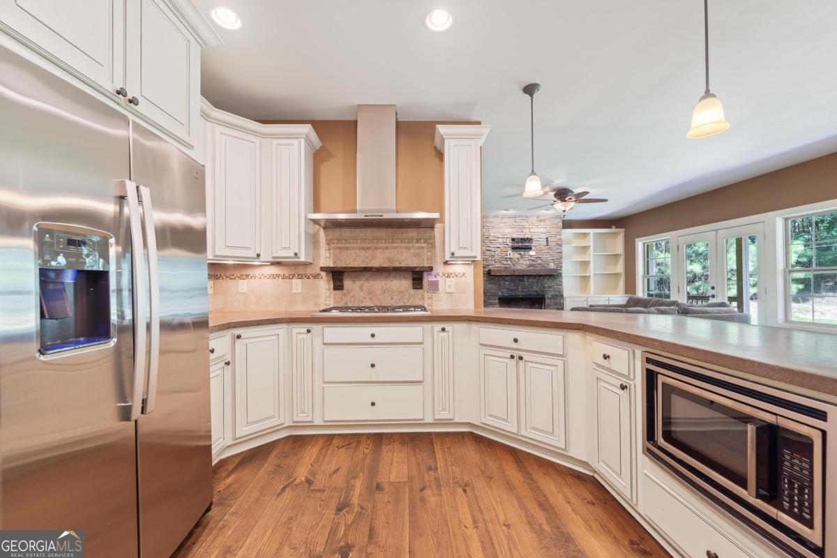 1991 Armour Bridge Road Greensboro, GA 30642 - Photo 12 of 41 a kitchen with stainless steel appliances granite countertop a stove a sink and white cabinets with wooden floor