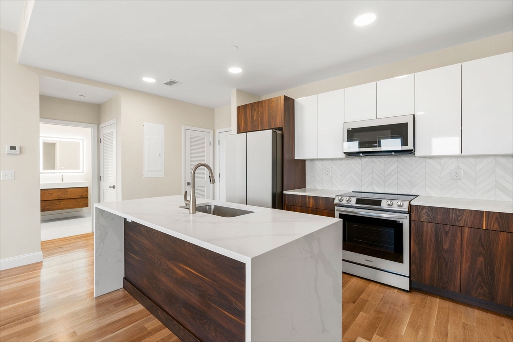 16 Taber Street, Unit 304 Boston, MA 02119 - Photo 7 of 11 a kitchen with stainless steel appliances granite countertop a stove a sink and a microwave