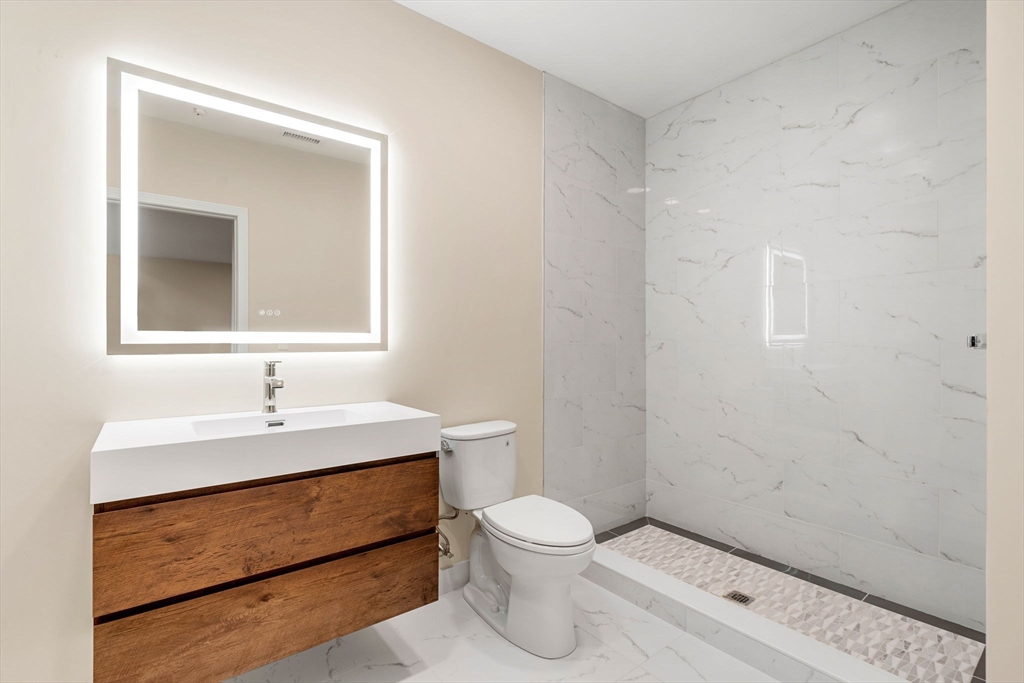 16 Taber Street, Unit 304 Boston, MA 02119 - Photo 10 of 11 a bathroom with a toilet sink and mirror