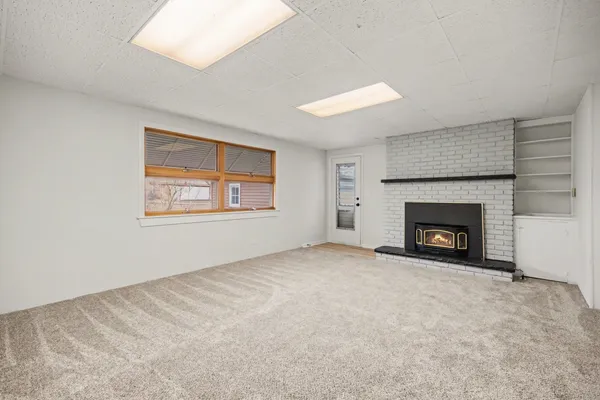 an empty room with windows and fireplace