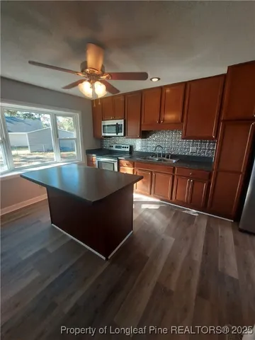 a kitchen with stainless steel appliances granite countertop a sink window and wooden floor