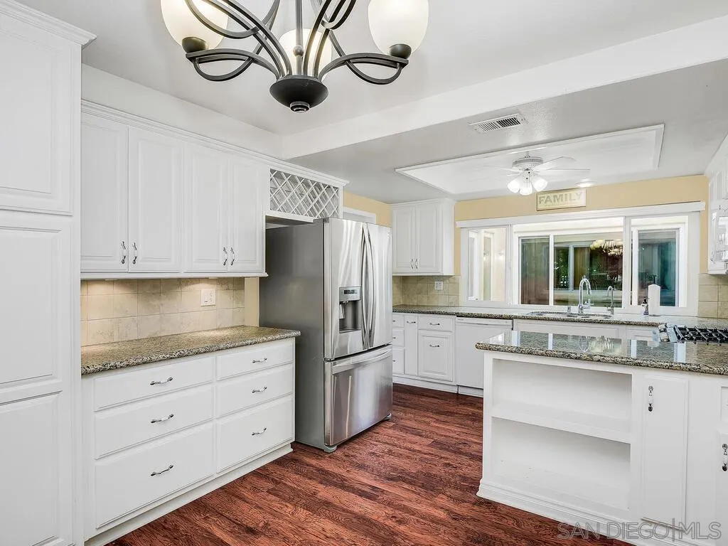 4708 Galicia Way Oceanside, CA 92056 - Photo 14 of 44 a kitchen with a refrigerator and white cabinets