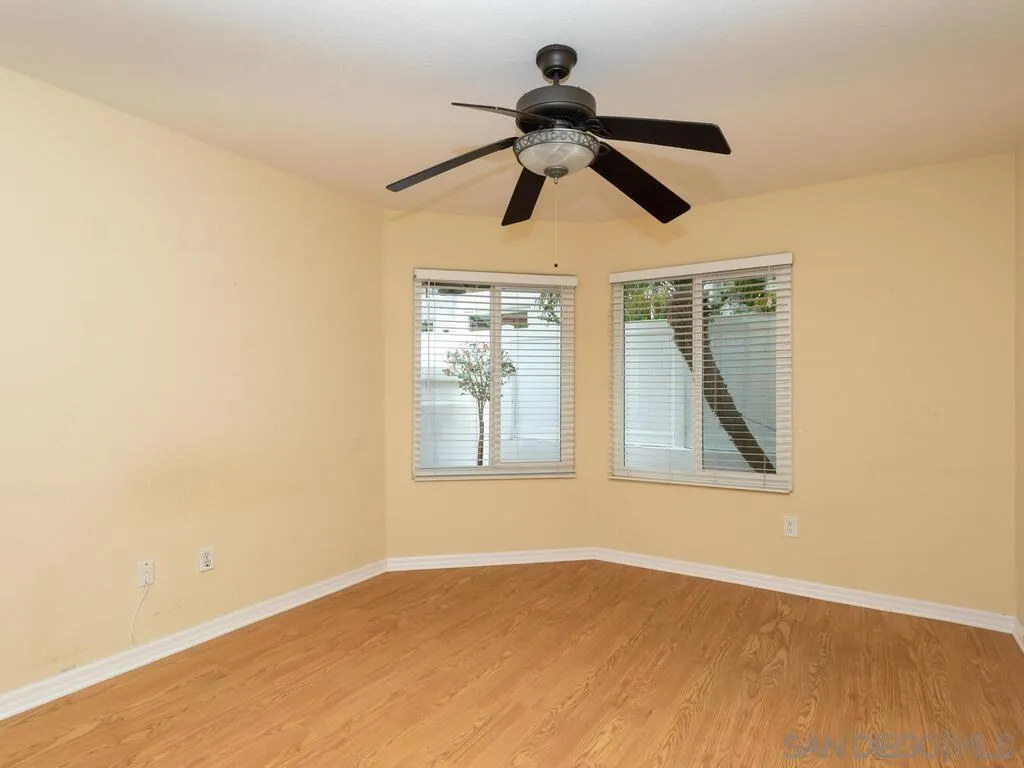 4708 Galicia Way Oceanside, CA 92056 - Photo 26 of 44 an empty room with wooden floor fan and windows