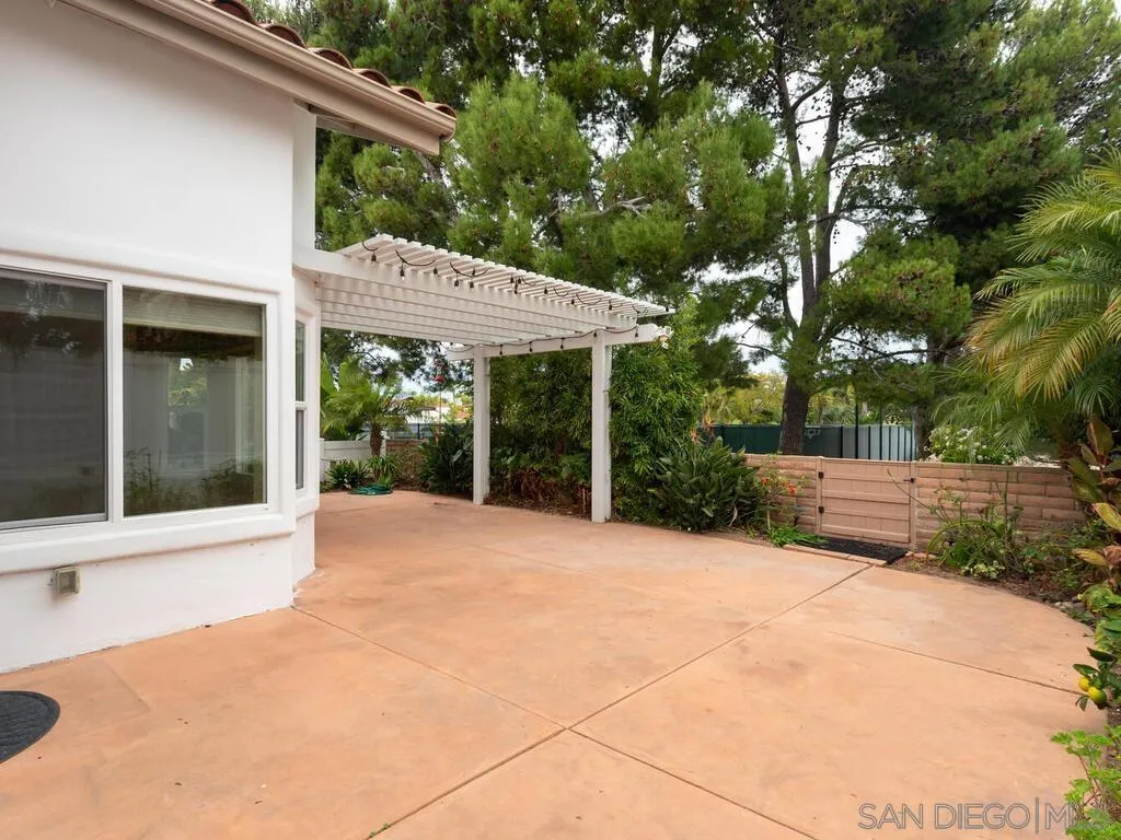 4708 Galicia Way Oceanside, CA 92056 - Photo 34 of 44 a view of a patio with a table and chairs under an umbrella with large trees