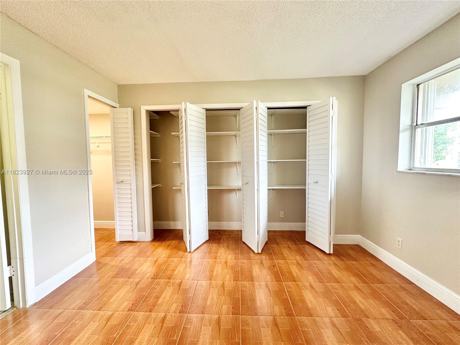 8001 Fairview Drive, Unit 107 Tamarac, FL 33321 - Photo 6 of 33 a view of an empty room with wooden floor and a window