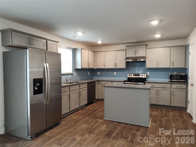 a kitchen with stainless steel appliances granite countertop a refrigerator sink and microwave