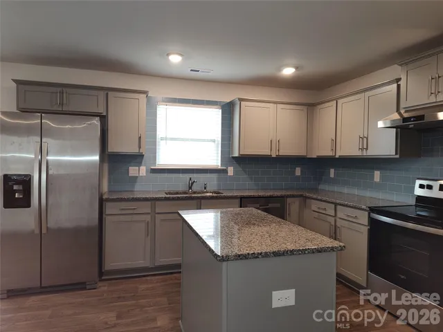 a kitchen with granite countertop a sink and stainless steel appliances