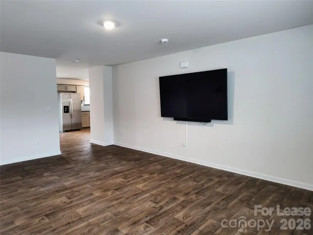 a view of an empty room with wooden floor and windows