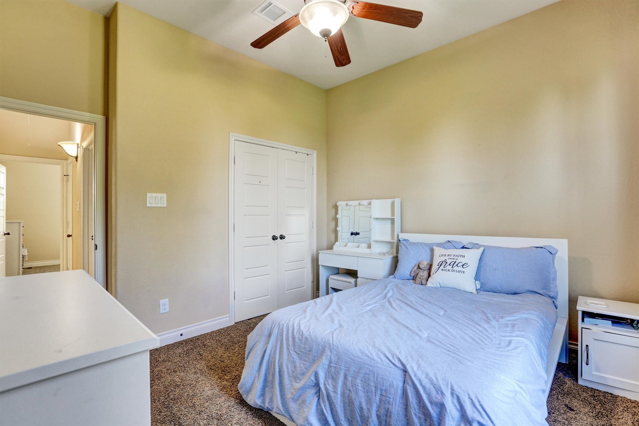8131 Brinkmeyer Road Needville, TX 77461 - Photo 27 of 49 Cozy bedroom with a ceiling fan, plush carpet, and ample natural light, featuring a comfortable bed and a charming vanity table.