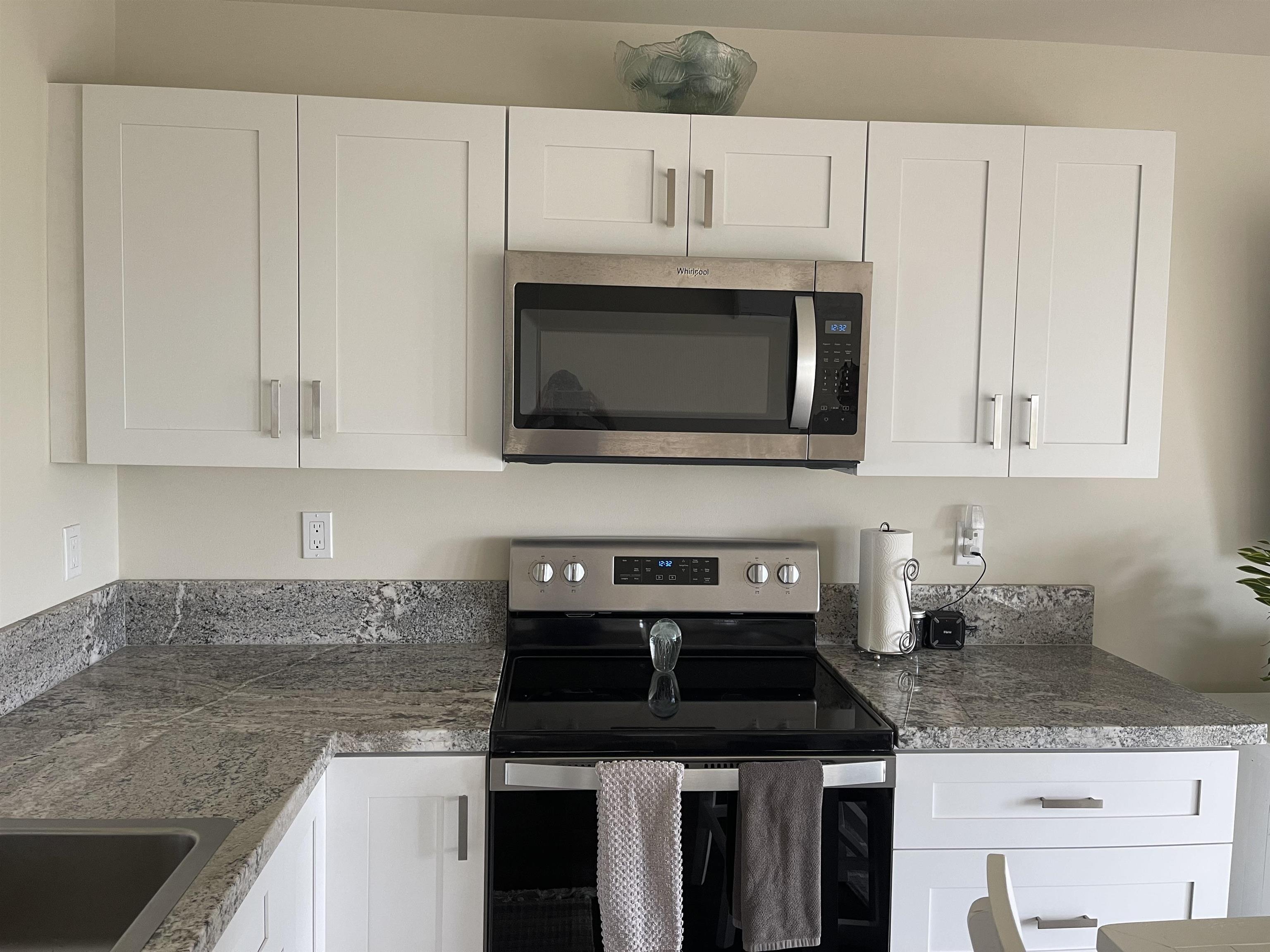 5510 Lower Honoapiilani Road, Unit C22 Lahaina, HI 96761 - Photo 2 of 13 a kitchen with granite countertop white cabinets and a stove top oven