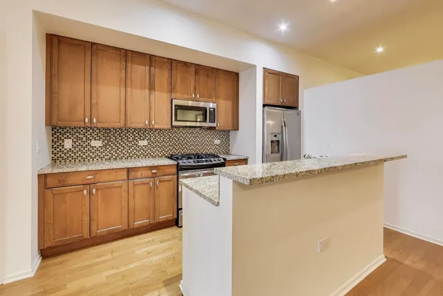 a kitchen with stainless steel appliances granite countertop a stove a sink and a refrigerator