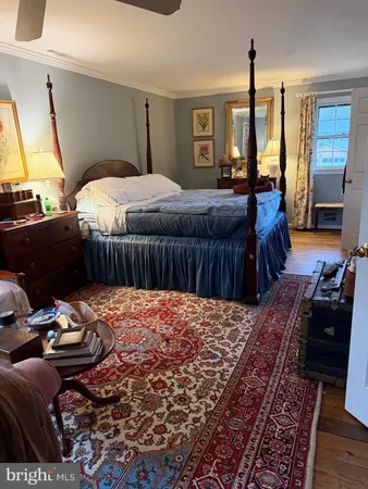 a bedroom with a bed a large window and wooden floor
