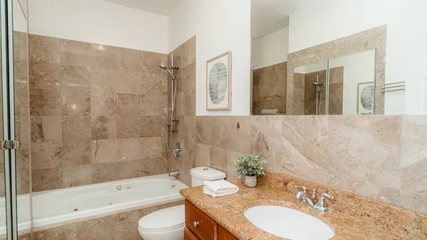a bathroom with a granite countertop sink a toilet and shower