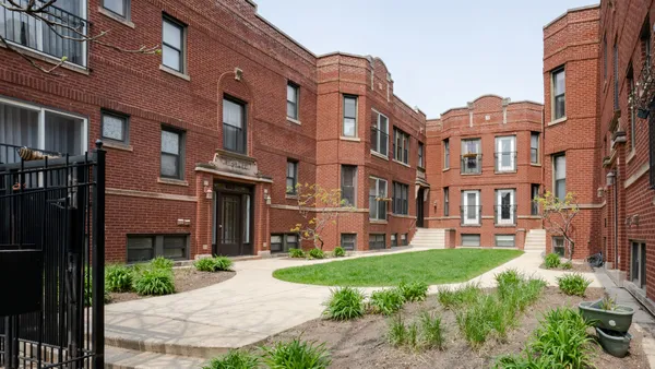 a front view of a building with a garden and plants