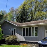 a view of a house with a yard plants and large tree