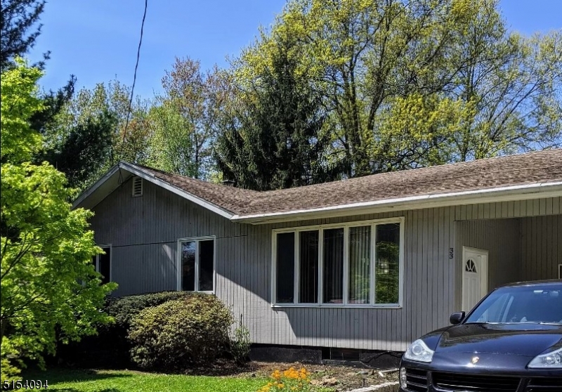 a view of a house with a yard plants and large tree