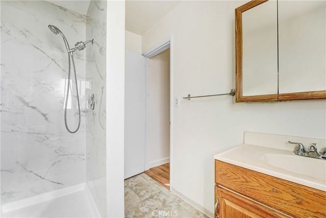 a bathroom with a granite countertop sink a mirror and shower